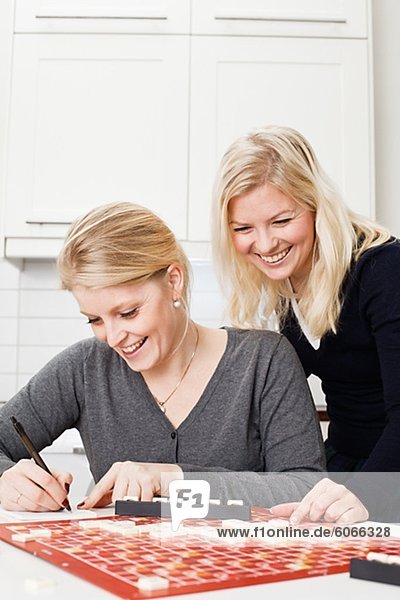 Zwei junge Frauen spielen Brettspiel in Küche