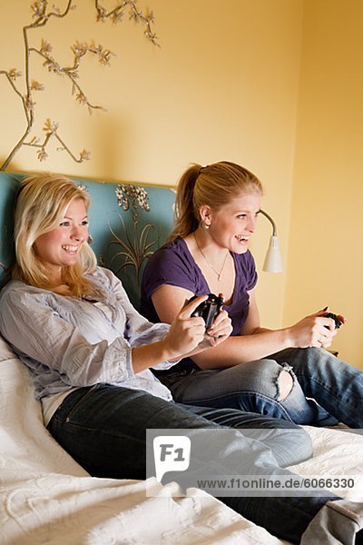 Two young women playing video game in bedroom