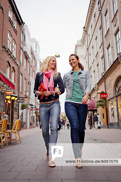 Two women walking arm in arm in street