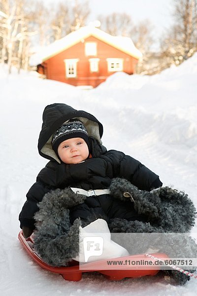 Baby girl sliding on toboggan in winter