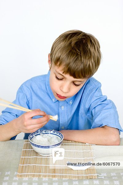 Portrait of boy eating rice with chopsticks