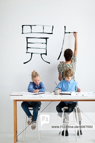 Boy und Girl mit weiblichen Lehrer während des Unterrichts Kunst Malerei