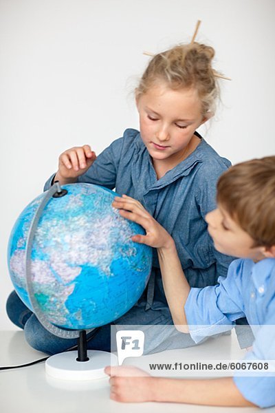 Junge und Mädchen lesen Globus