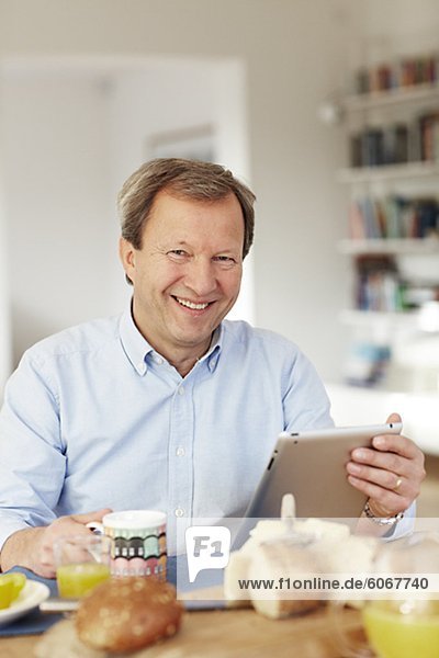 Porträt von älterer Mann mit digitalen Tablet am Tisch