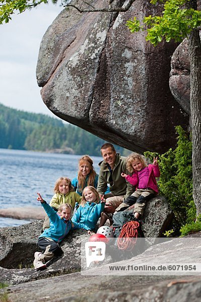 Familie mit vier Kinder sitzen in der Nähe von Felsen mit ihren Kletterausrüstung