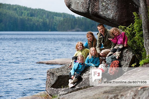 Familie mit vier Kinder sitzen in der Nähe des Felsens mit ihren Kletterausrüstung