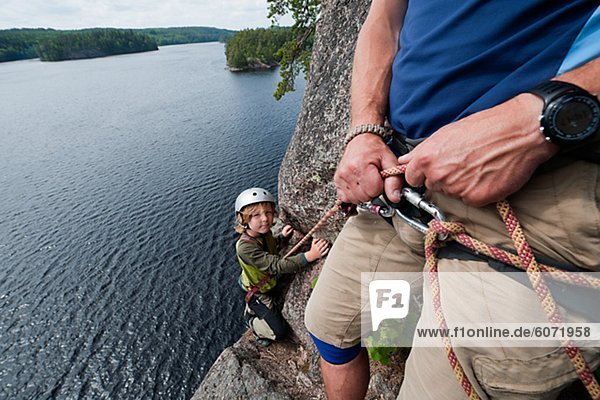 Father and son climbing together over lake
