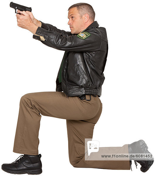 Polizist zielt mit Pistole  knieend