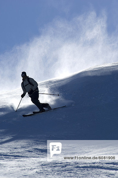 A man skiing against a bright blue sky.