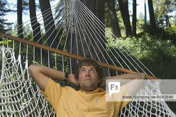 A young man relaxes in a hammock.