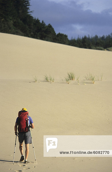 A backpacker making his way up an Oregon sand dune.