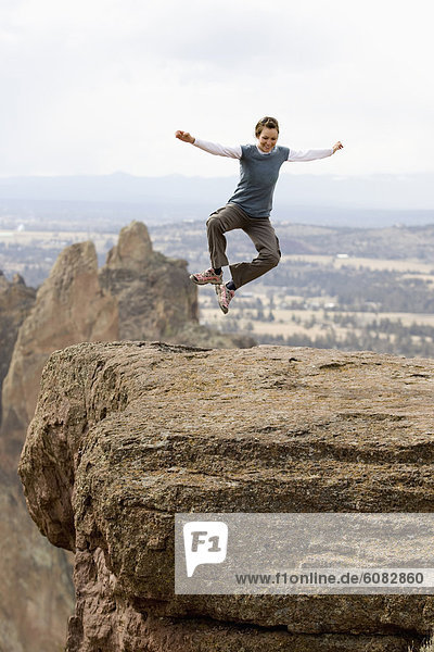 'A woman in an ''I Love Green'' shirt jumps for joy near the edge of the cliff in Smith Rock  Oregon.'