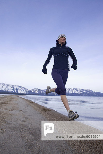 Woman running on beach in winter conditions in Lake Tahoe  California.