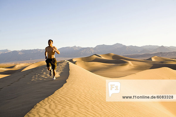 A shirtless man running on the Stovepipe Wells Dunes in Death Valley  California.