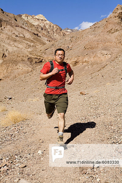 A young man with a backpack trail running in Death Valley National Park  California.
