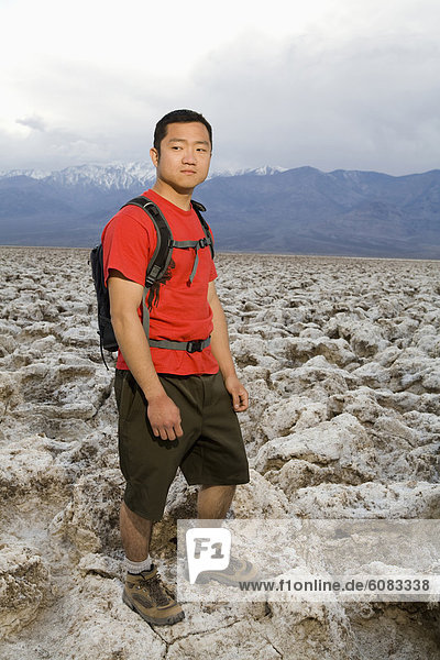 A young man with a backpack standing in the Devil's Golf Course section of Death Valley National Park.