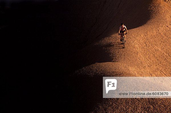 A woman mountain biking on a clay ridge at sunrise in Southern Utah.