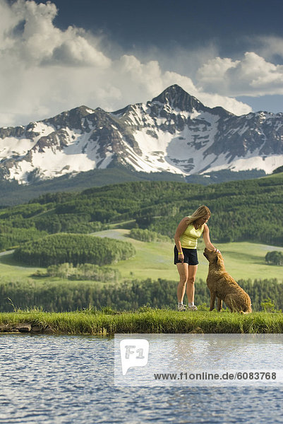 A woman petting her dog below Mount Wilson  Telluride  Colorado.