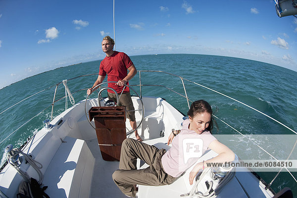 A man pilots a boat off of Florida while a woman sits nearby.