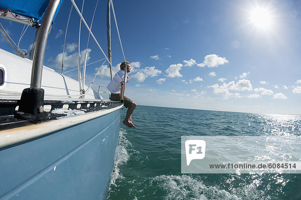 A man sits on the bow of a boat off of Florida.