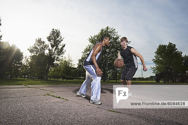 Two young men play one on one Basketball at Barstow Park in Vermillion  South Dakota (lit with flash).