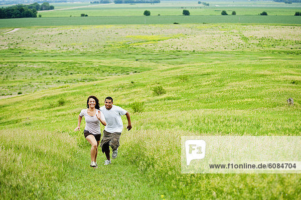 Young couple running on grass trail through a bright green field at Spirit Mound  South Dakota.