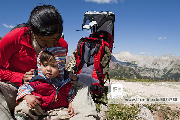 A mother kisses and plays with her 14 month old son at the top of Buckskin Pass (12 462ft) during a multiday backpacking trip in the Maroon Bells in Snowmass Wilderness.