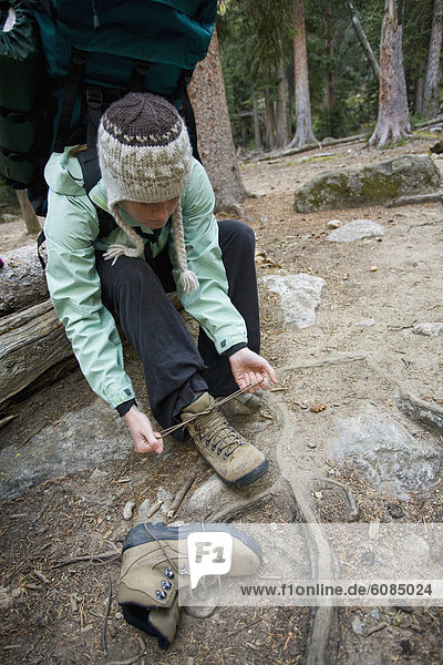 A woman changes her hiking boots while seated on a log in Rocky Mountain National Park  Colorado.