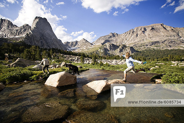 A couple and their dog cross a stream while hiking in the Cirque of the Towers  Wind River Range  Wyoming.