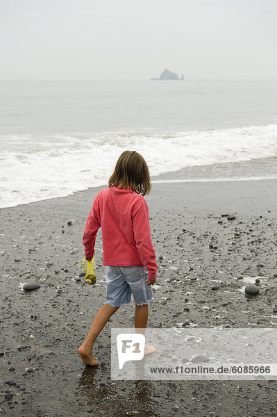 A young girl collects rocks along the Washington coast.