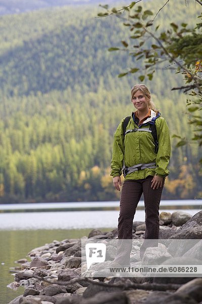 Portrait of young female hiker on edge of lake deep in Glacier National Park.
