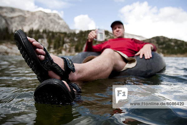 A man floats an inner tube in an alpine lake  Mirror Lake  in the Snowy Range  Wyoming.