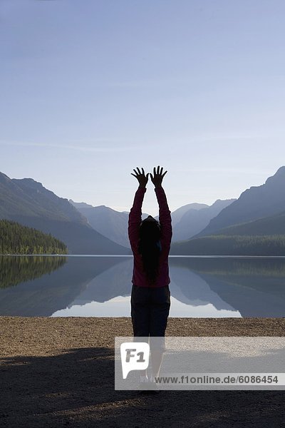Silhouette of a woman practicing outdoor yoga at a remote lake in Glacier National Park.