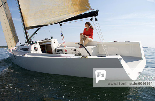 A woman enjoying a sunny day on board a daysailer on Casco Bay  Maine.