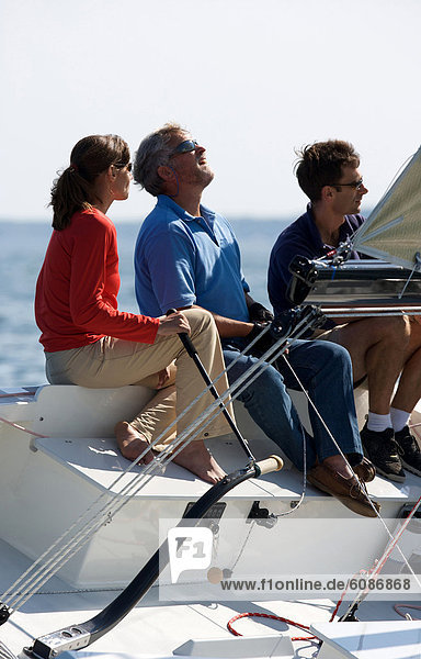 Three adults enjoying a sunny day on board a daysailer on Casco Bay  Maine.