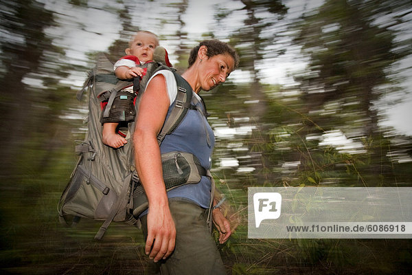A woman carries her child in a backpack  Hinchinbrook Island  Queensland  Australia.