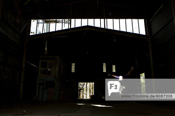 A skater ollies in an abandoned warehouse on the Central Coast  New South Wales  Australia.