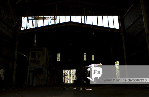 A skater performs a kick flip in an abandoned warehouse on the Central Coast  New South Wales  Australia.