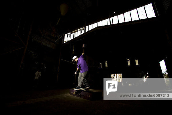 A skater performs a smith grind at an abandoned warehouse on the Central Coast  New South Wales  Australia.