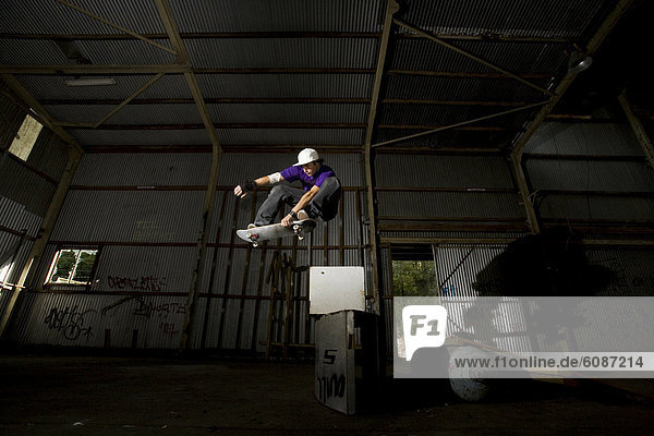 A skater performs a grab at an abandoned warehouse on the Central Coast  New South Wales  Australia.