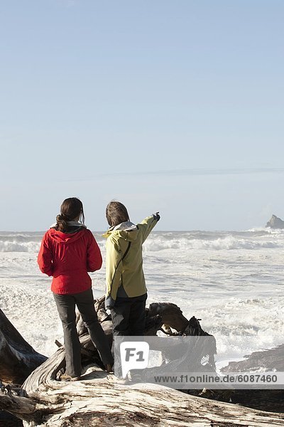 Two woman looking out over the massive swells in the Pacific Ocean.