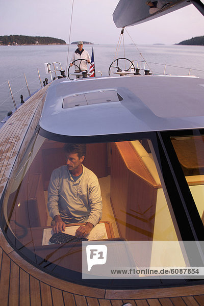 A crew navigates a racing yacht home at dusk using high tech instruments.