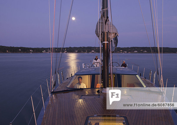 A crew navigates a racing yacht home at dusk using high tech instruments.