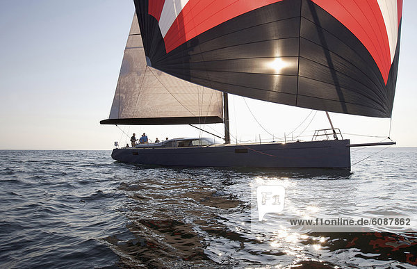 A crew races a modern ocean-going sailing yacht under spinnaker.