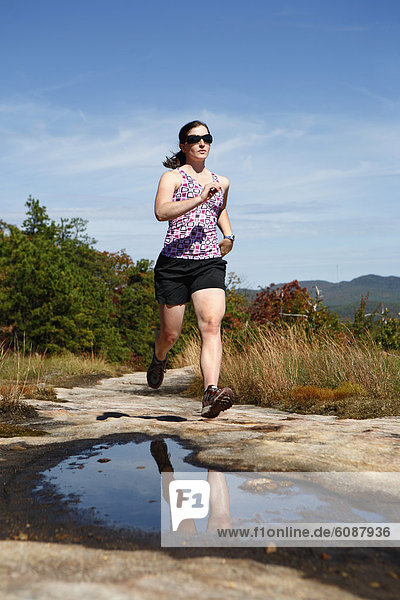 Woman running on a rocky trail in North Carolina.