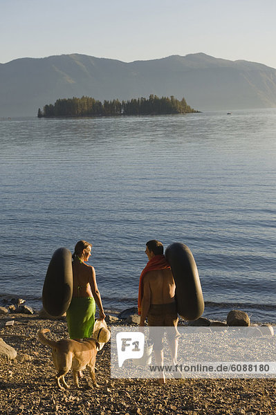 A young couple prepare to float on the lake in inner tubes during a hot summer day.