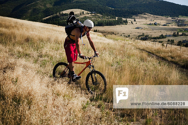 A male mountain biker rides off the trail and through the grass of Mt. Sentinel  Missoula  Montana.