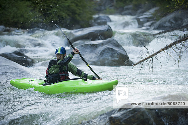 A whitewater kayaker continues down a rocky section of a high moutain river.