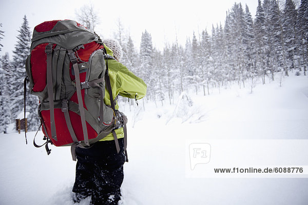 A young woman hikes with a backpack in fresh powder in the Wasatch Mountains  Utah.