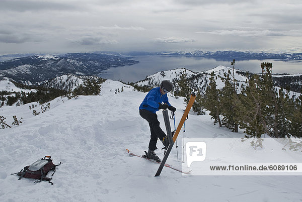 A young man takes his skins off his skis after skinning up a mountain high above Lake Tahoe  Nevada.